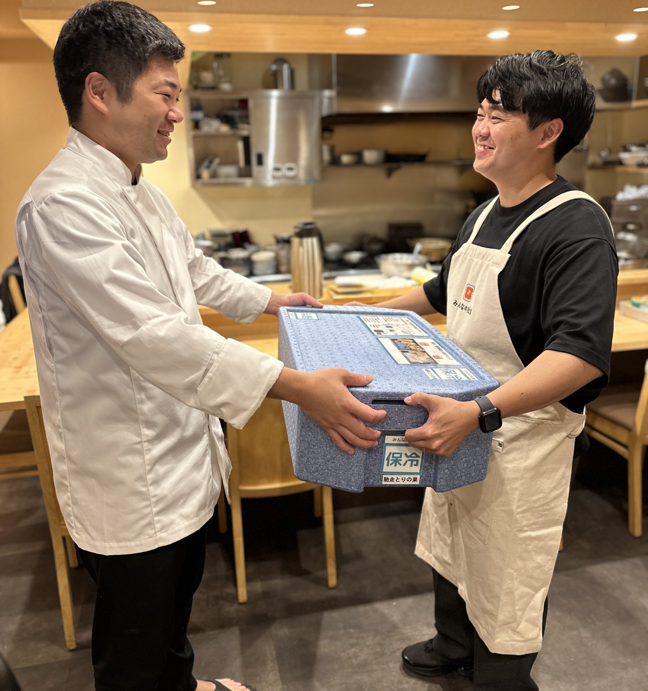 飲食店で料理の入った保冷BOXを受け取る配送パートナー